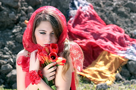 close-up photography of woman wearing red scarf and holding red and yellow tulip flowers thumbnail