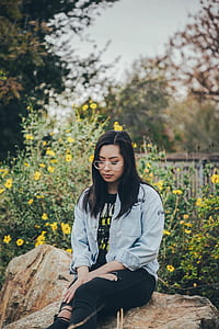 woman sitting on rock while looking downward thumbnail