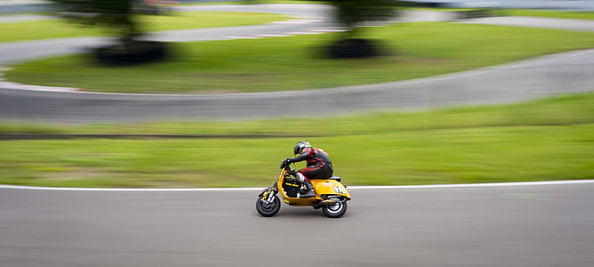 person riding yellow motor scooter on concrete road thumbnail