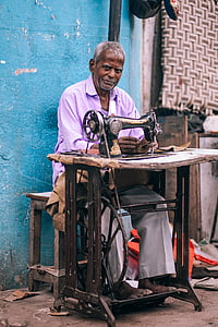 man sitting on chair fixing textile by using sewing machine thumbnail