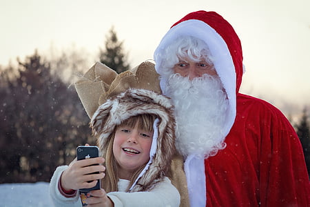 child taking selfie next to man in Santa Claus costume thumbnail