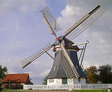 gray and white windmill near red brick house thumbnail