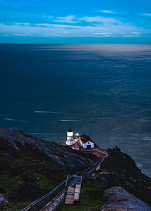 white and red lighthouse near body of mountain thumbnail