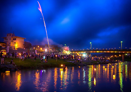 group of people gather river bank with fireworks display thumbnail