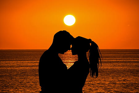 man and woman hugging by the beach with ocean on the horizon during sunset thumbnail