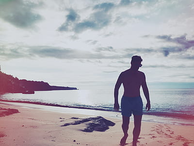 man wearing board shorts standing in shoreline thumbnail