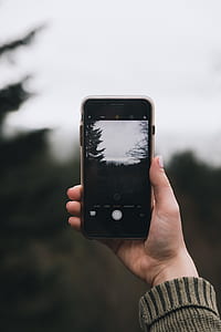 pershon taking a photo of mountain with green trees thumbnail