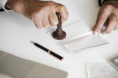 man holding brown wooden stamp near pen thumbnail