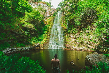 man standing in front of waterfalls during daytime thumbnail