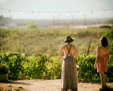 two woman standing near bush during daytime thumbnail
