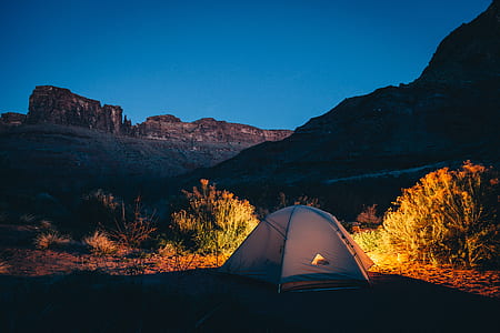 white done tent on brown soil and cliffs under night sky thumbnail