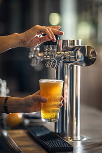 person filling clear glass with beverage on gray dispenser thumbnail