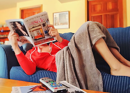 woman reading magazine lying on sofa thumbnail