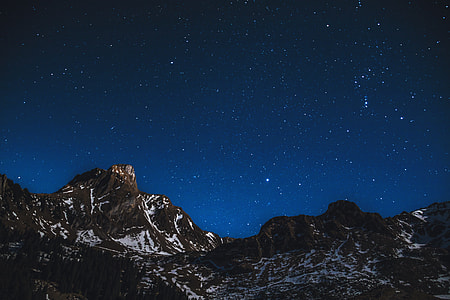 Snow-covered mountains at night with stars in sky thumbnail