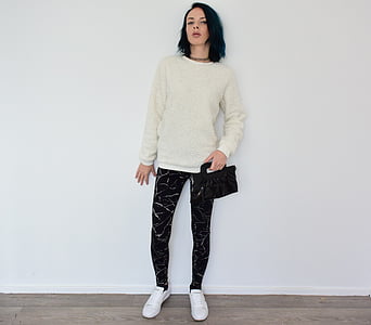 woman wearing grey crew-neck sweater and black pants leaning on wall thumbnail