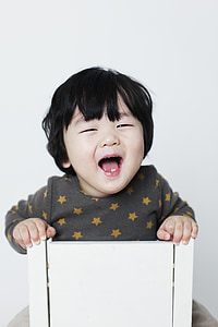 laughing baby inside white wooden box thumbnail