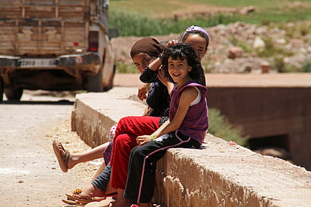 selective focus photography of two girls and one boy sitting on concrete bench at daytime thumbnail