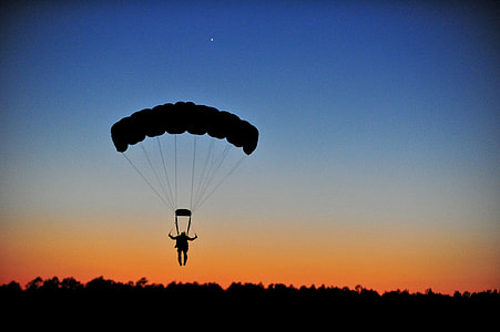 silhouette photography of person on parachute while on air during golden hour thumbnail