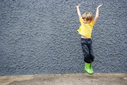 boy jumping beside grey wall thumbnail