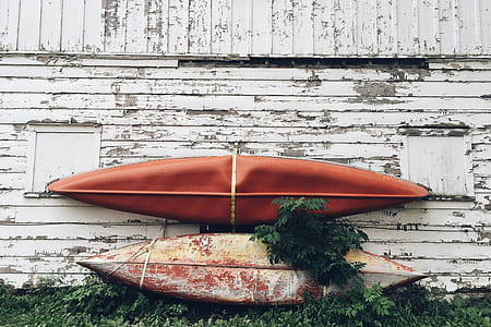 two orange kayak boats on white wooden wall thumbnail