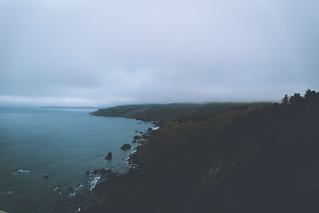 aerial photography of mountainside beside body of water during daytime thumbnail