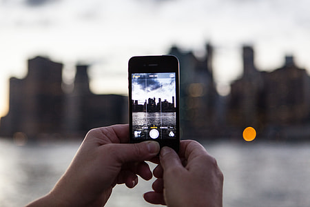 A person captures the sunset over the Manhattan skyline in New York with their iPhone mobile smartphone. Image taken from DUMBO, Brooklyn thumbnail