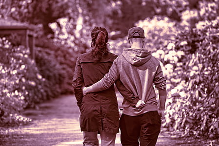 couple walking on pathway next to plants during daytime thumbnail