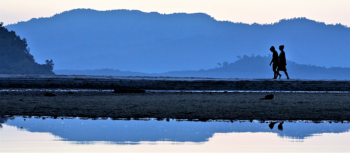 two people walking near body of water during daytime thumbnail