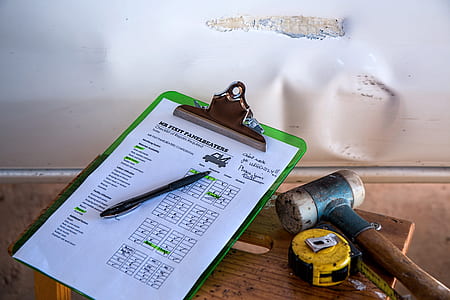 green clip board beaside of yellow tape measure and mallet on table thumbnail