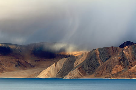 aerial photography of body of water near mountains under white sky at daytime thumbnail