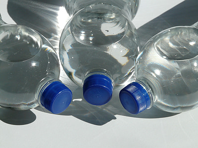 three sealed blue capped bottles lying on white surface thumbnail