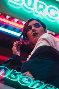 woman standing beside blue neon signs thumbnail