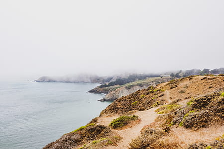 Hills Beside Body of Water Covered With Fog thumbnail