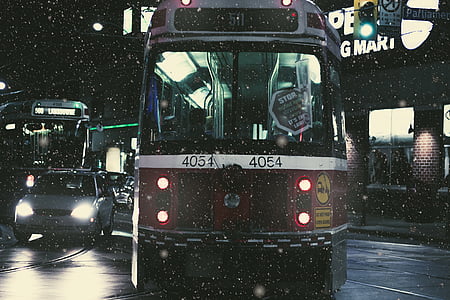 red and white train traveling on road during nighttime thumbnail