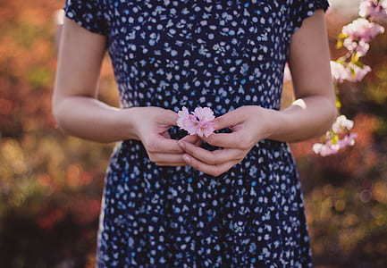 woman in blue short-sleeved dress holding pink flowers in shallow photograpy thumbnail