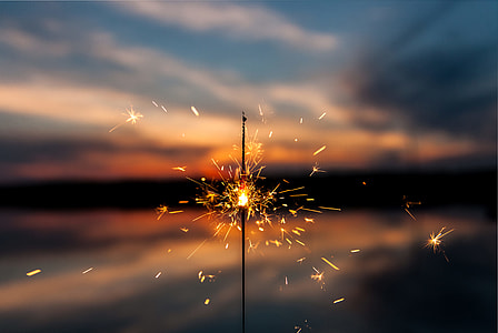 selective focus photography of sparkler firework under blue and white sky thumbnail