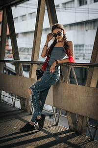 woman taking off sunglasses while leaning against the metal bridge thumbnail