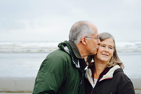 man kissing woman at seashore during daytime thumbnail