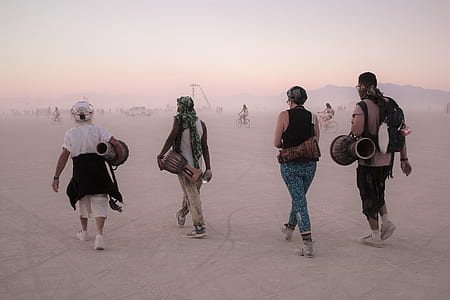 two men and women carrying percussion instruments walking on landscape field thumbnail