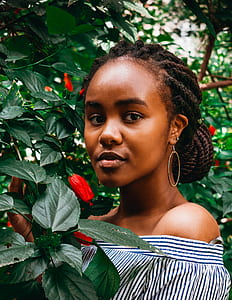 woman wearing white-and-black striped top standing near red flowering tree thumbnail