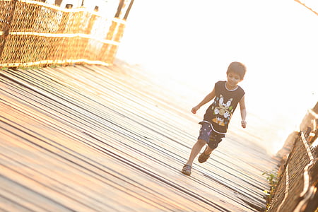 boy wearing black sonic printed tank top running on brown wooden bridge thumbnail