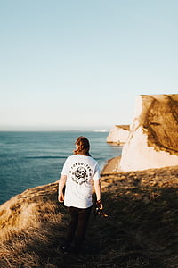 person standing on mountain near ocean thumbnail