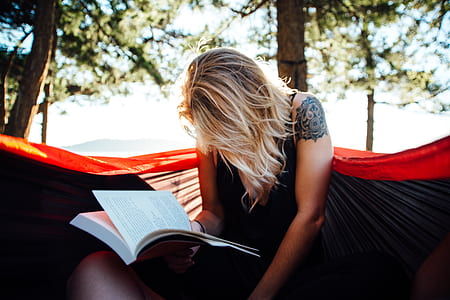 woman reading book on hammock at daytime thumbnail