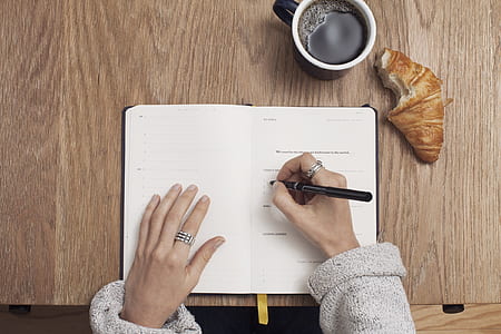 woman in sweater writing on her planner wallpaper thumbnail