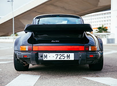 Rear view of a black sports car with low ground clearance thumbnail