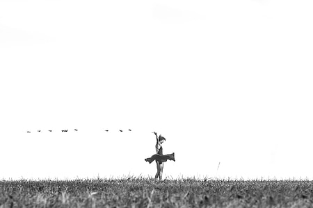 grayscale photography of woman in mini dress standing on grass thumbnail