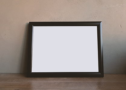 black photo frame leaning on brown wall thumbnail
