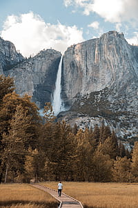 man in a white shirt walking on a wooden pathway leading to Yosemite Falls, Yosemite National Park thumbnail