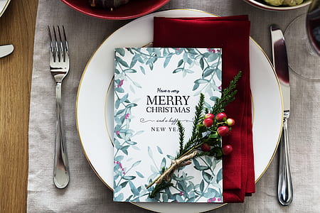 white porcelain plate with silverware on top of table with Christmas card thumbnail