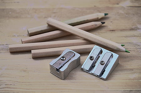 five brown pencils and two silver sharpeners on wooden surface thumbnail